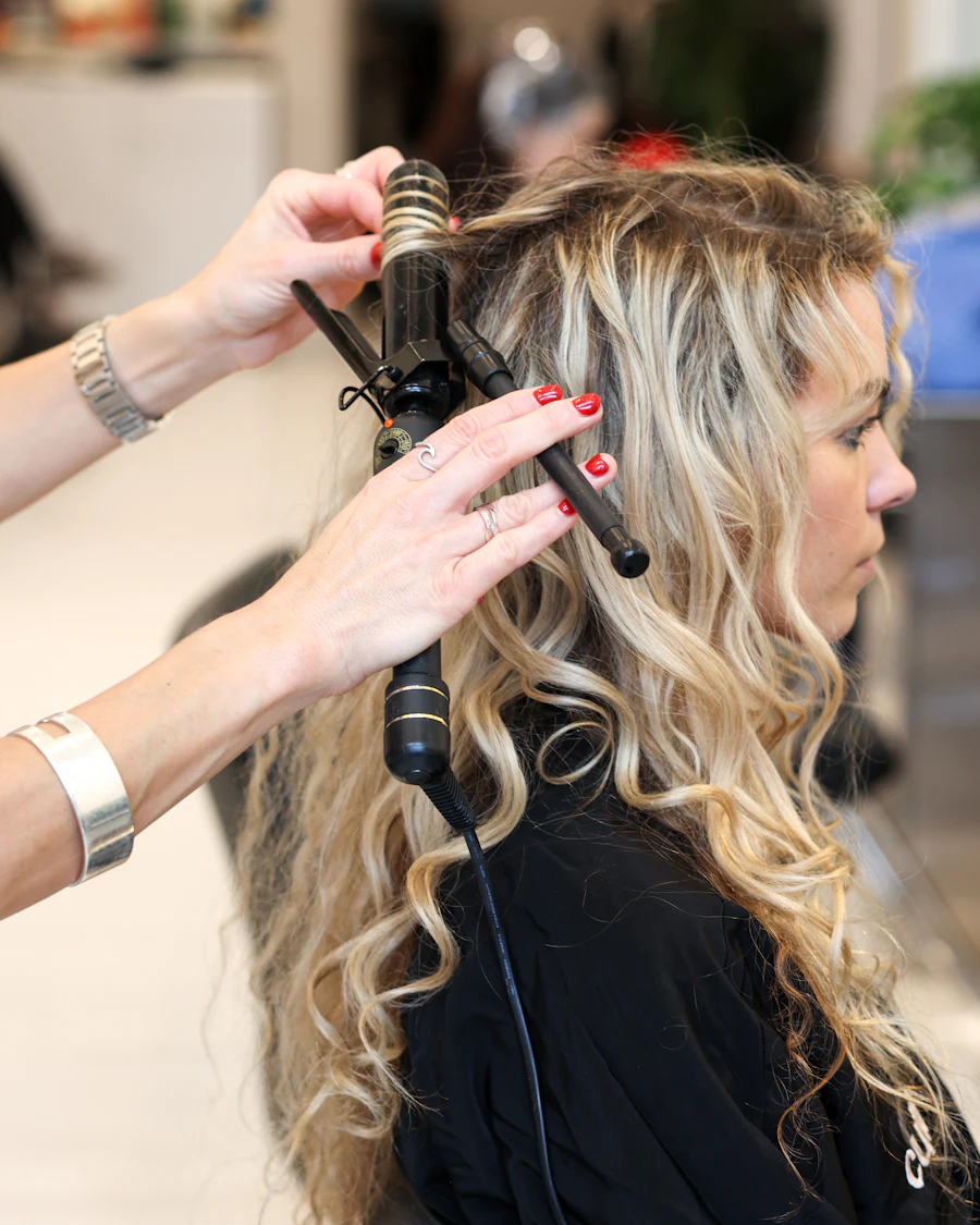 Estilista dando forma a ondas en cabello rubio